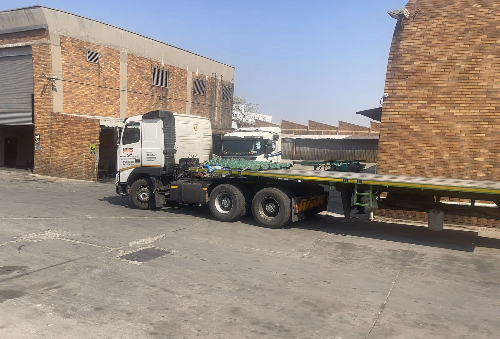 Blue tri-axle flatbed trailer loaded with galvanised steel pipes